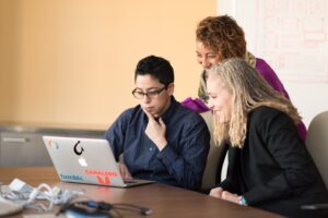 Three software engineers looking at a single laptop